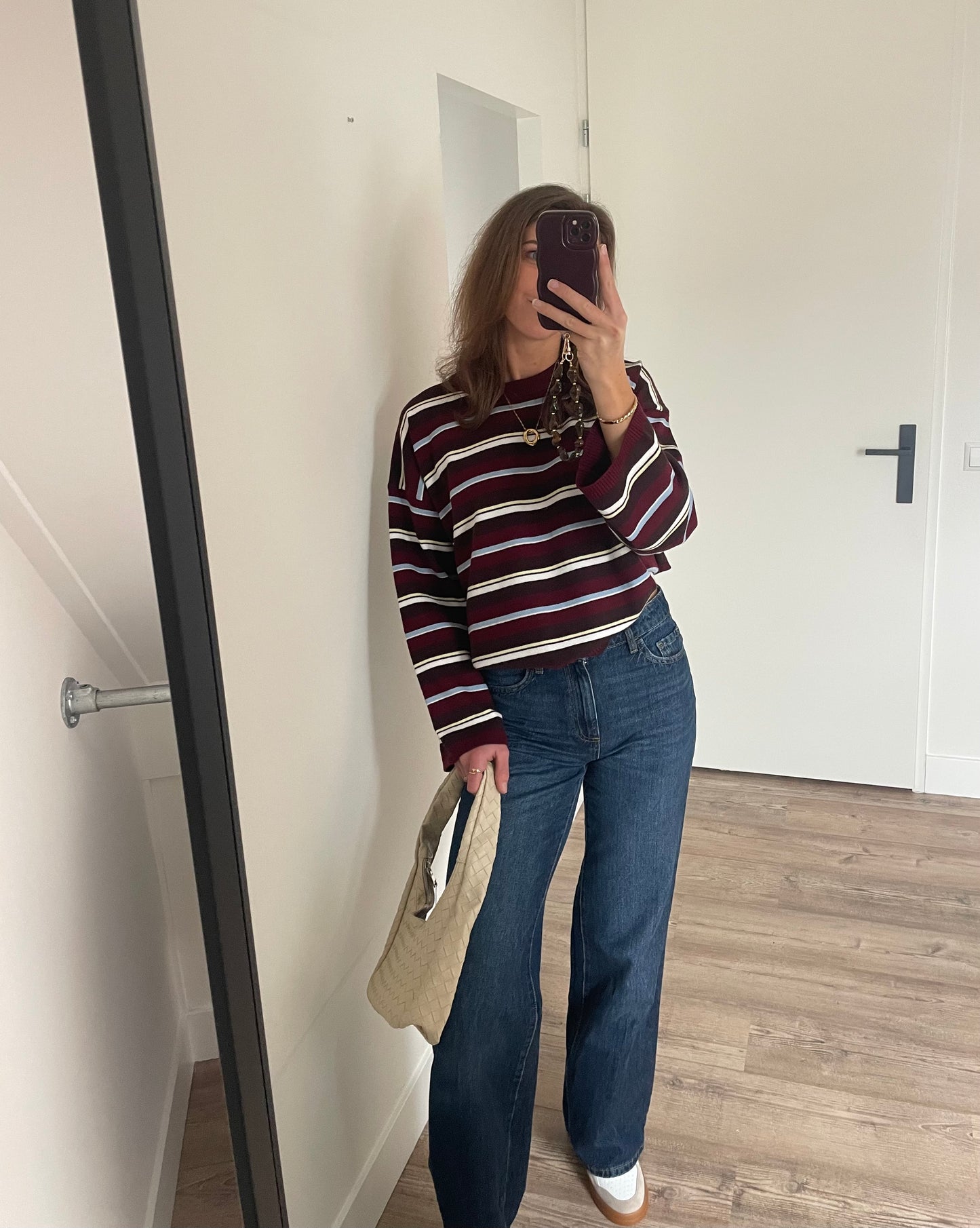 Fashionable outfit voor dames, wide leg jeans met gestreepte trui, tas en gouden cirkel ketting 