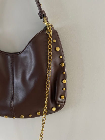 Close-up van gouden studs en details op bruine tas - By LIV Fashion