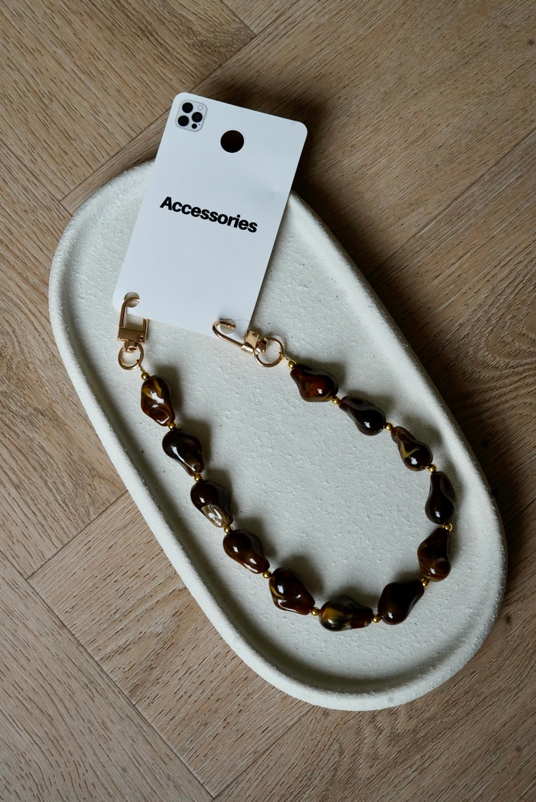 Telefoonkoord met bruine grafisch gevormde bedels en gouden details