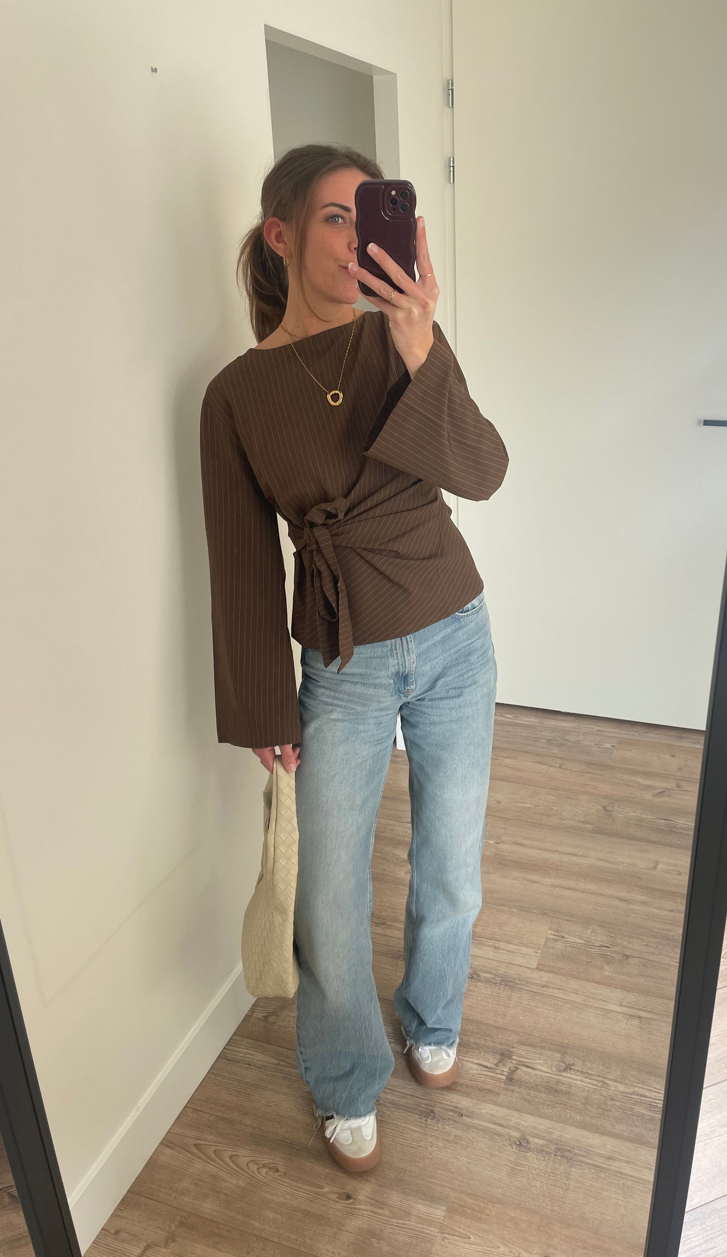 betaalbare casual chic outfits dames, flared bow blouse met gouden lange cirkel ketting, beige tas en jeans 