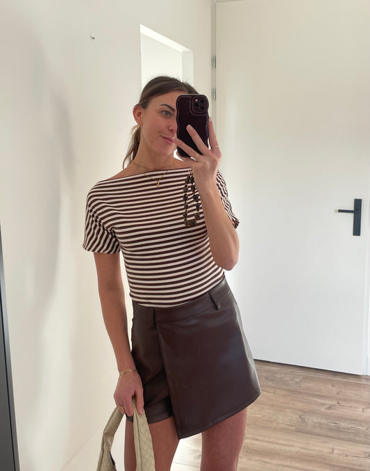 Outfit van leren bruine skort met gestreepte top met boothals en beige gevlochten tas 